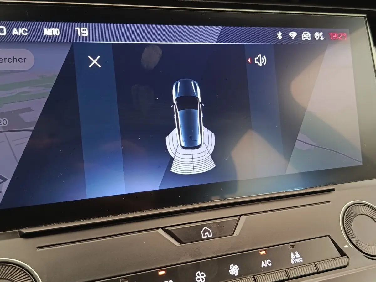 Écran tactile intérieur montrant la vue aérienne du véhicule Peugeot 308 blanc avec capteurs de stationnement arrière actifs.