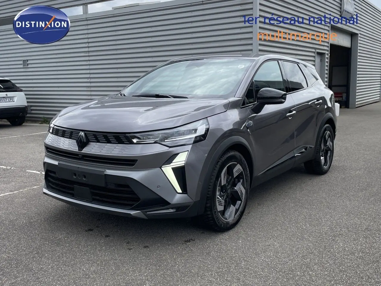 Renault Symbioz gris cassiopée métal en 3/4 avant droit, avec feux LED distinctifs et jantes noires stylisées.