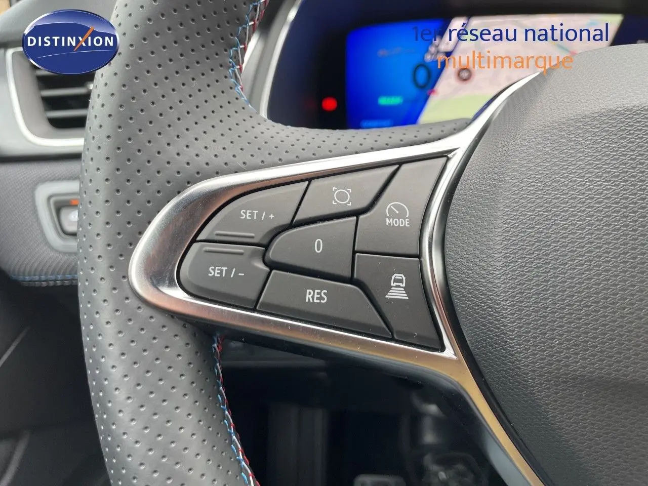 Gros plan sur les commandes au volant en cuir perforé gris du Renault Symbioz 2026, avec affichage numérique bleu en arrière-plan.