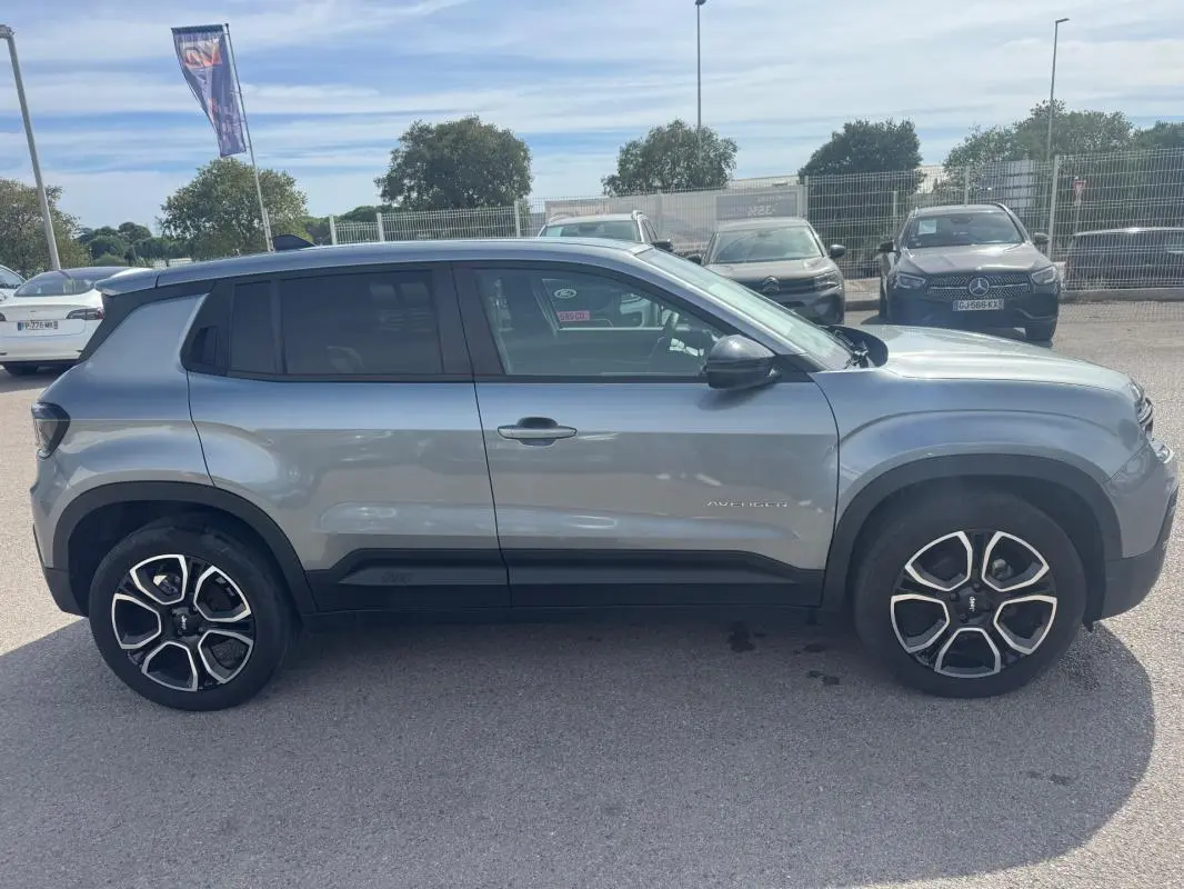 Vue de profil côté gauche du Jeep Avenger gris foncé 2025, avec jantes distinctives et toit noir contrastant.