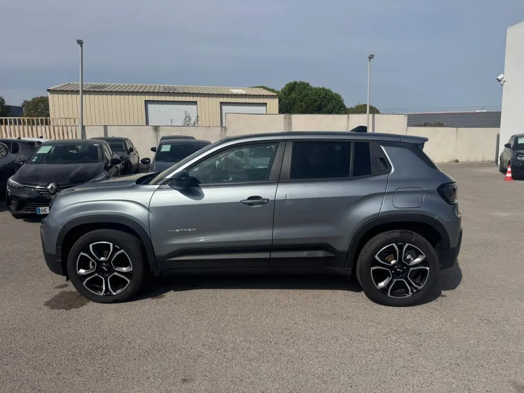 Vue de profil côté gauche d'un Jeep Avenger gris foncé 2025 avec jantes noires et toit contrasté.