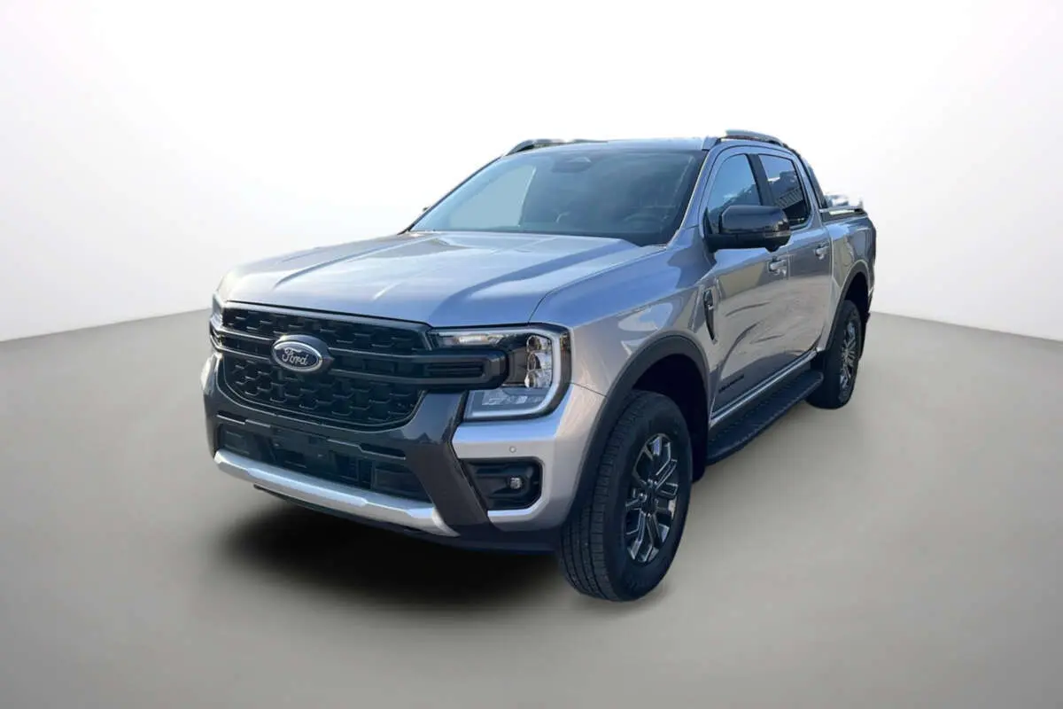 Ford Ranger 2.0 Wildtrak Plus gris iconic en 3/4 avant droit avec barres de toit et jantes alu 18 pouces.