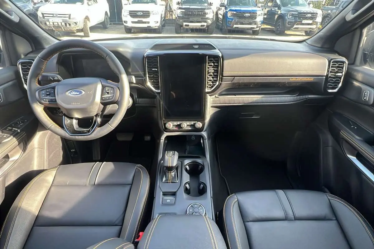 Vue intérieure avant du Ford Ranger Wildtrak 2026 gris iconic, avec volant cuir multifonctions et écran tactile vertical.