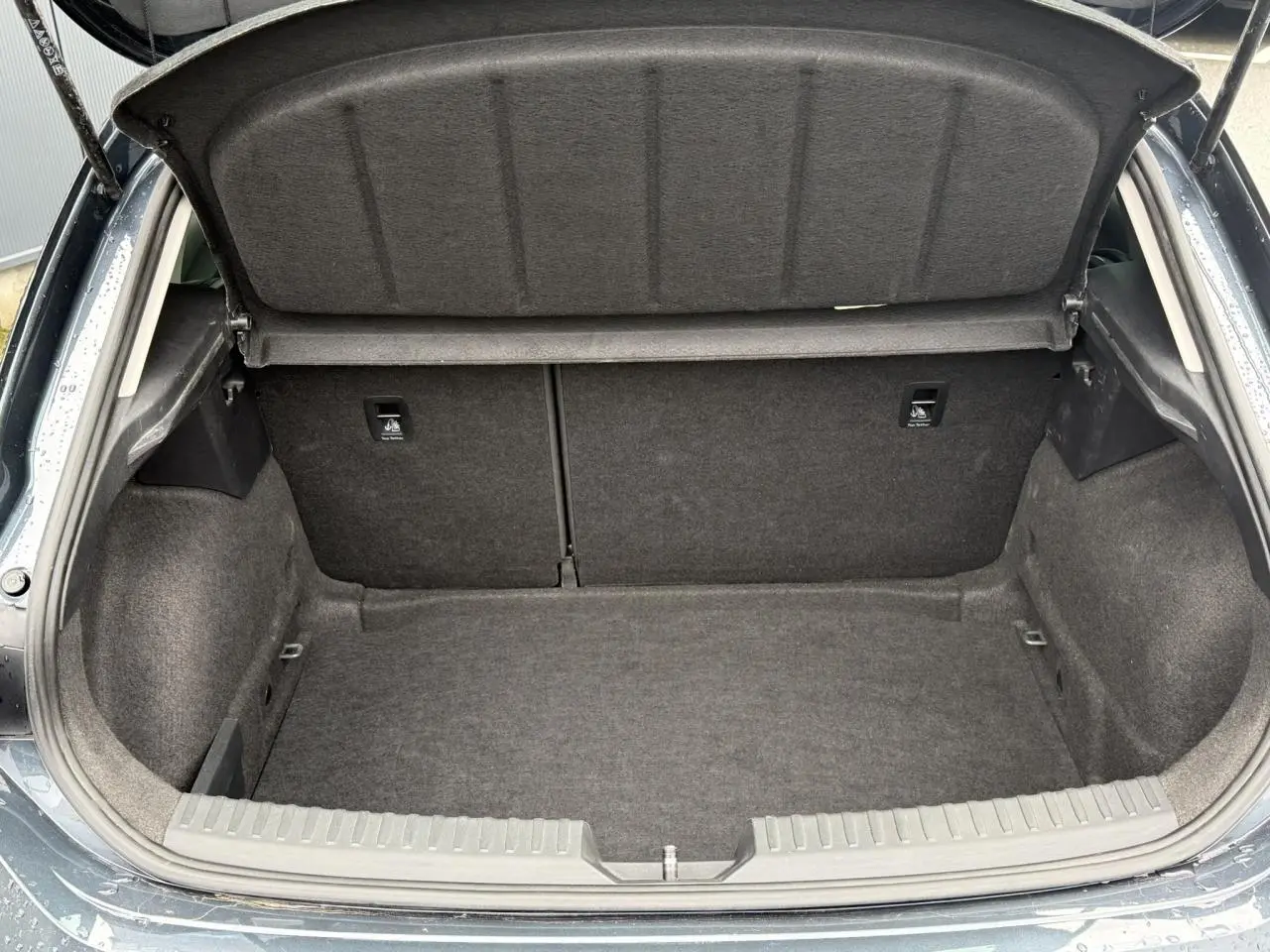 Coffre ouvert vu de l'arrière d'une SEAT LEON 1.5 TSI 115 Style gris magnétique, intérieur de coffre en tissu gris.