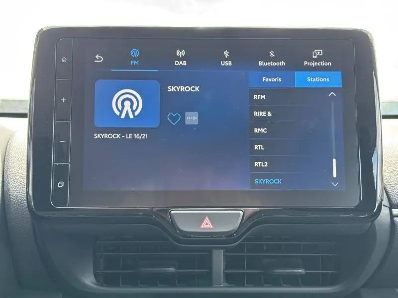Écran tactile central de la Toyota Yaris 2025 affichant la radio Skyrock, avec boutons de commande sur cadre noir.