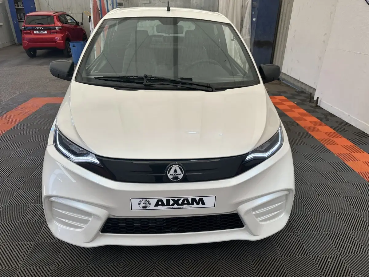 Vue avant d'une Aixam Ambition 0.5 City Pack blanche avec calandre noire et phares LED distinctifs.