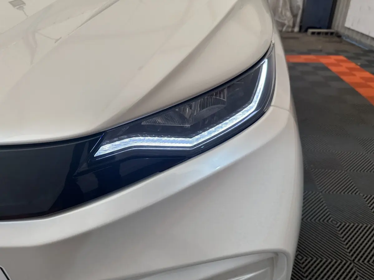 Gros plan sur le phare avant droit blanc de l'AIXAM AMBITION 0.5 CITY PACK 2026 avec éclairage LED distinctif.