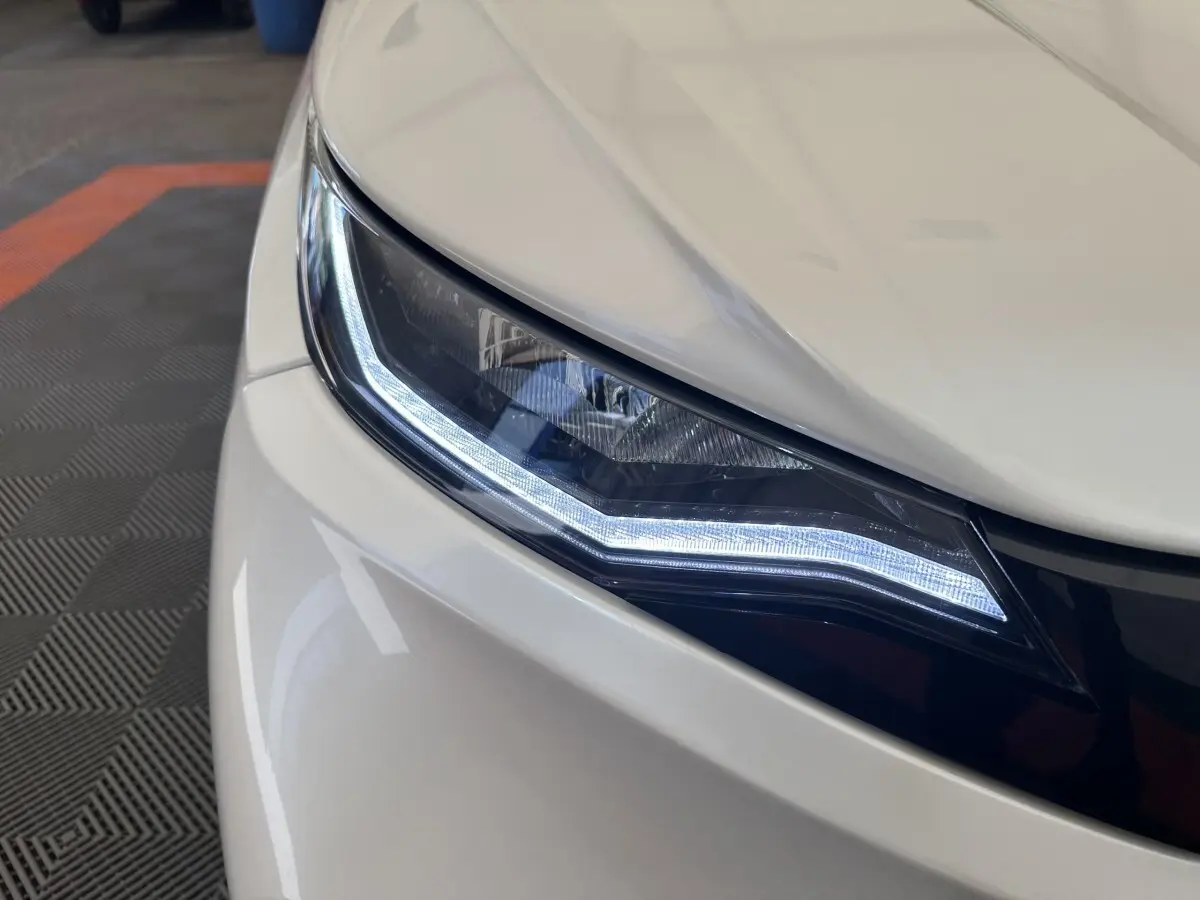 Gros plan sur le phare avant droit blanc de l'AIXAM AMBITION 0.5 CITY PACK 2026 avec éclairage LED distinctif.