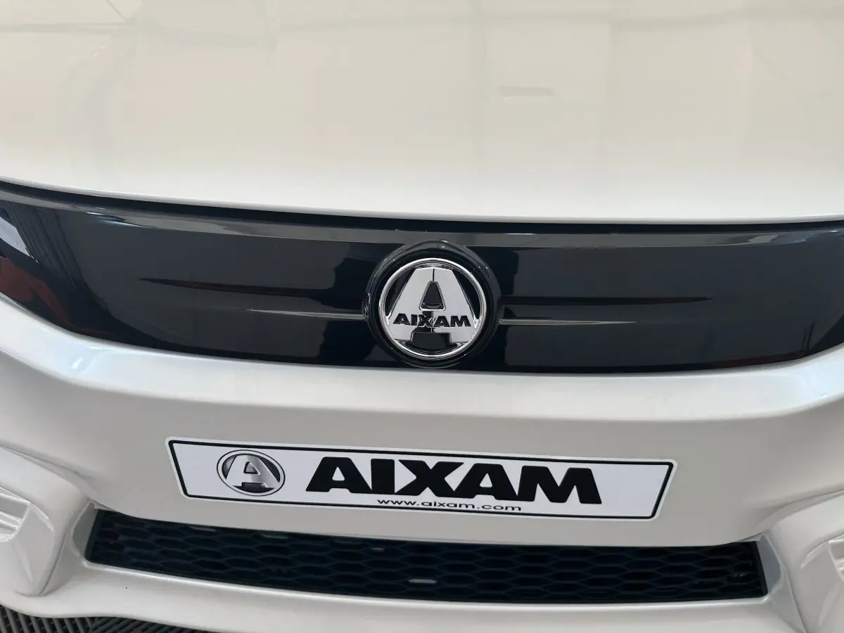 Gros plan sur la calandre avant blanche de l'AIXAM AMBITION 0.5 CITY PACK avec logo central et plaque AIXAM.