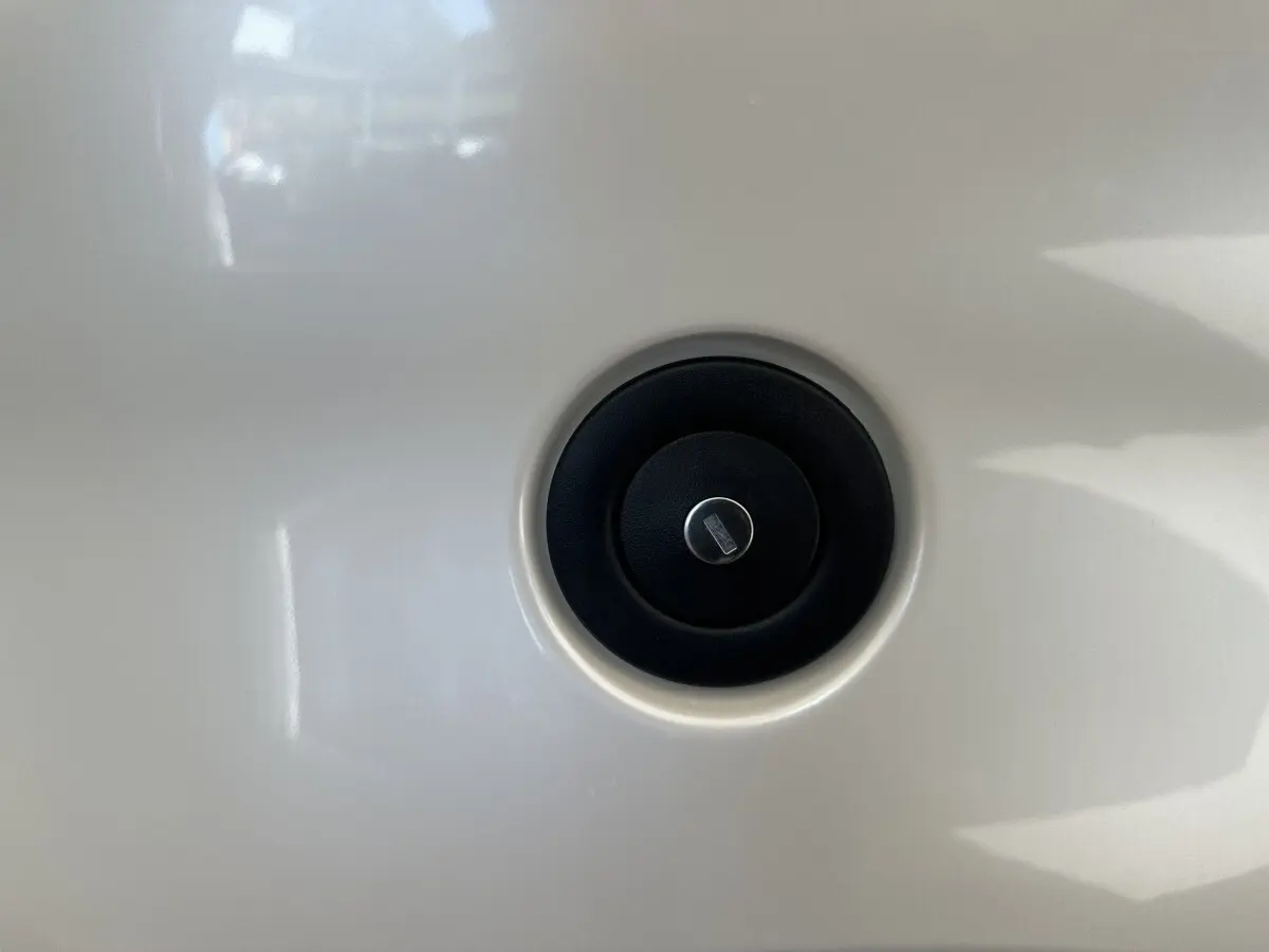 Gros plan sur le bouchon de réservoir noir circulaire sur la carrosserie blanche d'une Aixam Ambition 0.5 City Pack 2026.