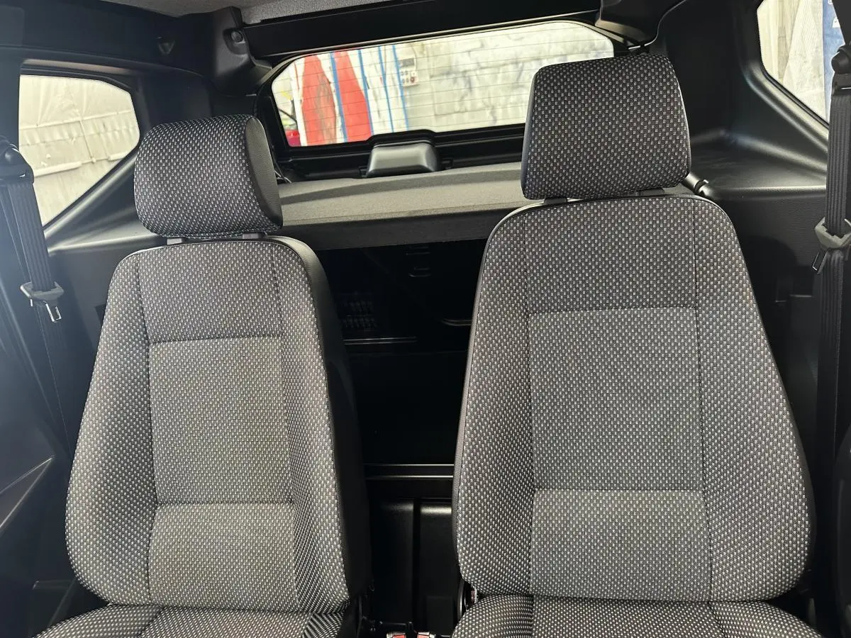 Vue intérieure frontale des sièges avant gris à motifs de l'AIXAM AMBITION 0.5 CITY PACK 2026, sans visibilité extérieure.