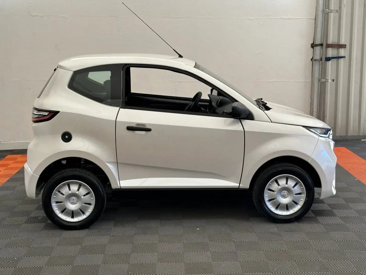 Vue de profil côté gauche d'une AIXAM AMBITION 0.5 CITY PACK blanche avec rétroviseur caméra côté conducteur.