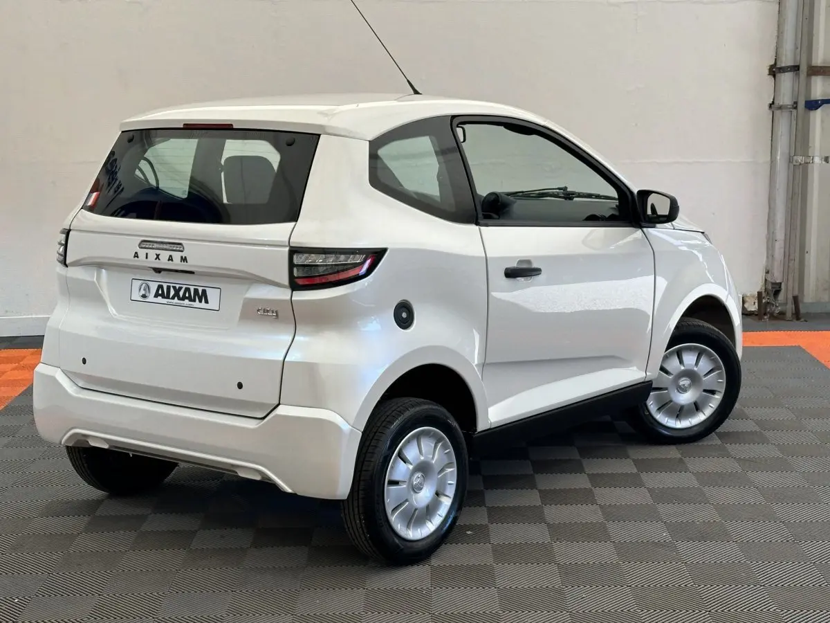 Vue 3/4 arrière droite d'une Aixam Ambition 0.5 City Pack blanche avec rétroviseur caméra côté gauche.