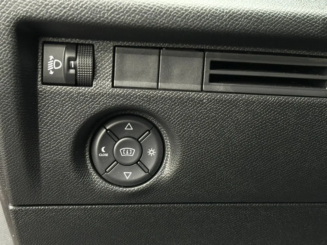 Détail du tableau de bord noir avec commandes d’éclairage et réglage des phares du Citroën C4 Hybrid 2025.
