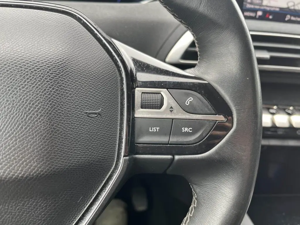 Gros plan sur les commandes au volant droit en cuir noir du Peugeot 3008 2017, avec boutons multifonctions et tableau de bord en arrière-plan.