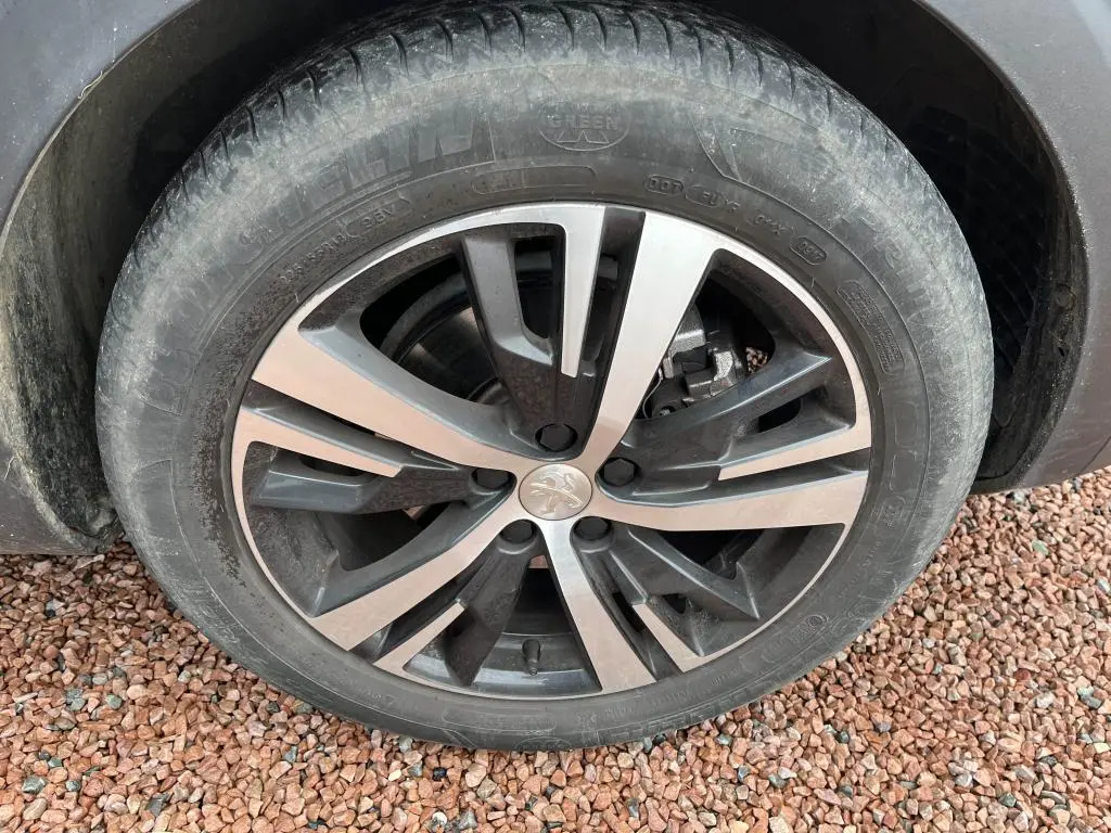 Gros plan sur la roue avant droite du Peugeot 3008 2017, jante alliage bicolore avec logo Peugeot au centre.