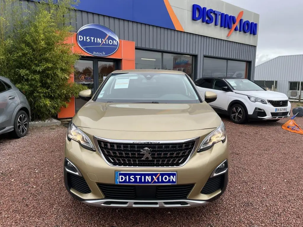 Vue de face du Peugeot 3008 jaune clair métallisé, avec calandre noire et logo lion au centre, devant un concessionnaire.