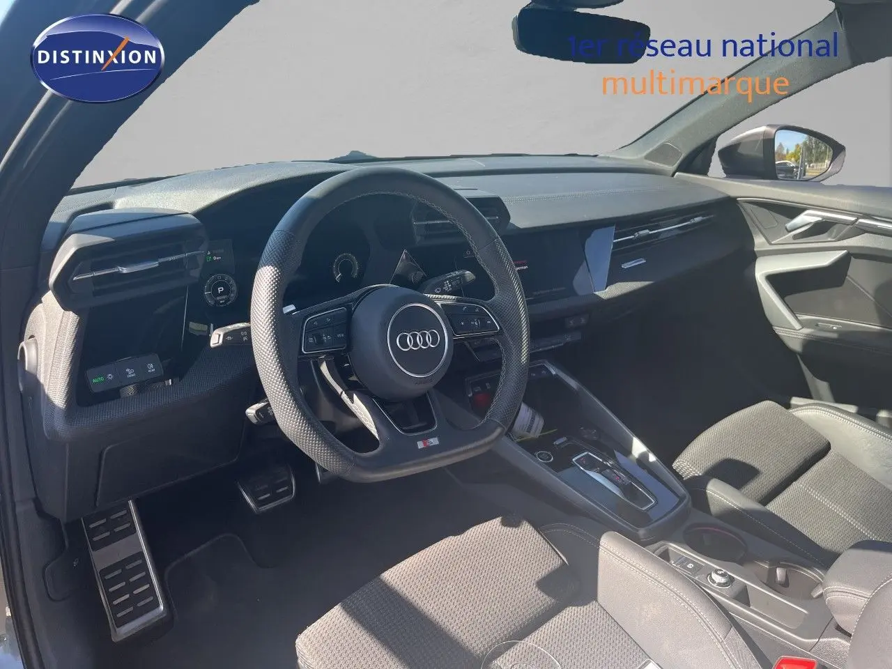 Intérieur de l'Audi A3 Sportback 40 TFSIe 2025 vu côté conducteur, tableau de bord noir et volant multifonction S-Line.