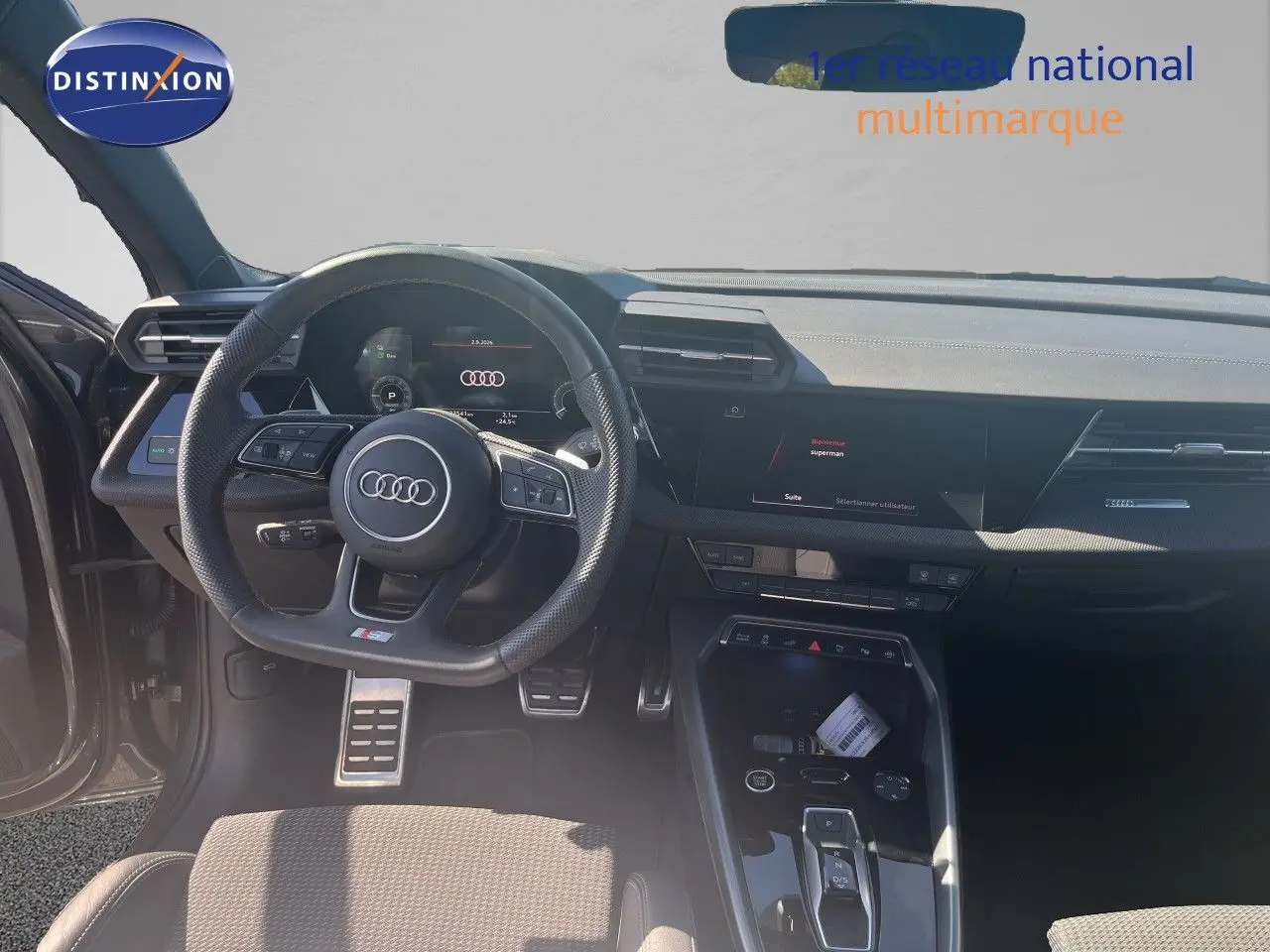 Vue intérieure de l'Audi A3 Sportback 2025, tableau de bord et volant multifonction en cuir noir, ambiance moderne et épurée.
