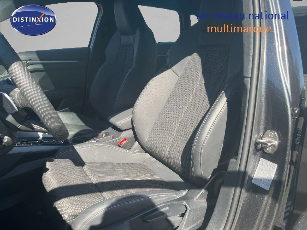 Vue intérieure côté conducteur de l'Audi A3 Sportback gris Daytona, mettant en valeur les sièges en tissu et cuir noir.