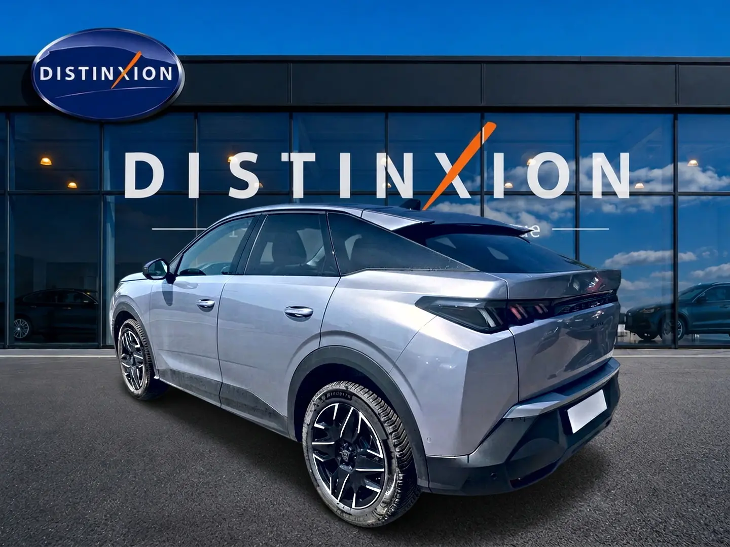 Vue 3/4 arrière droite d’un Peugeot 3008 gris 2025 avec jantes alu noires devant une vitrine Distinxion.