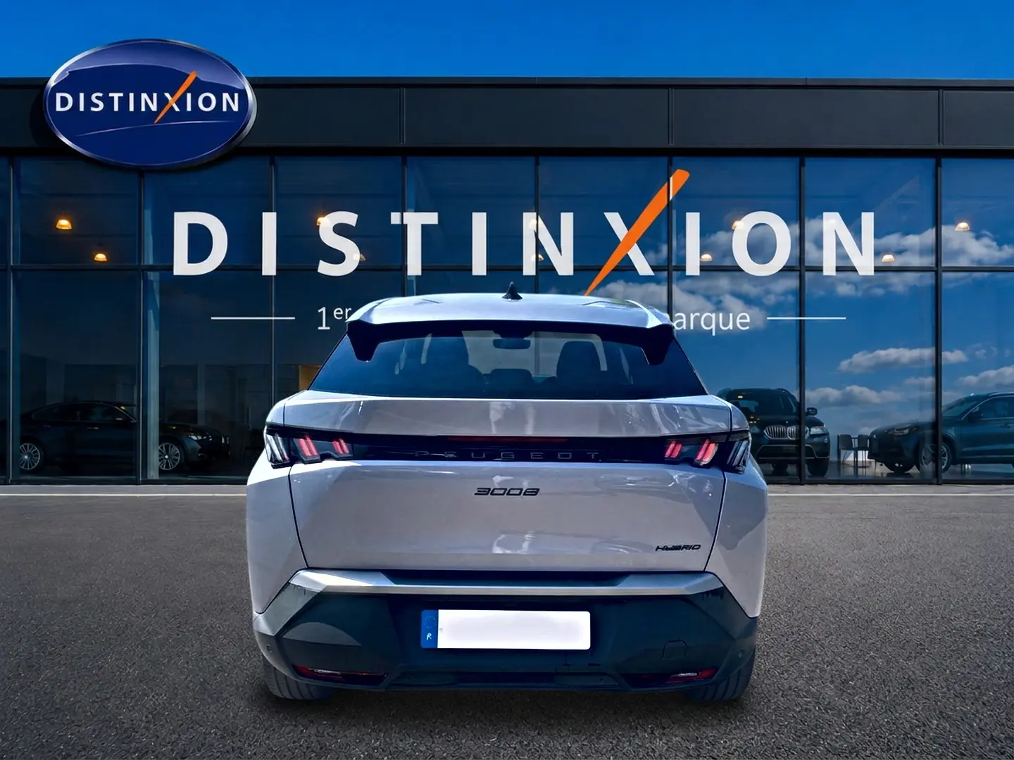 Vue arrière d'un Peugeot 3008 gris 2025 hybride, avec feux arrière LED et becquet arrière visible devant une vitrine Distinxion.