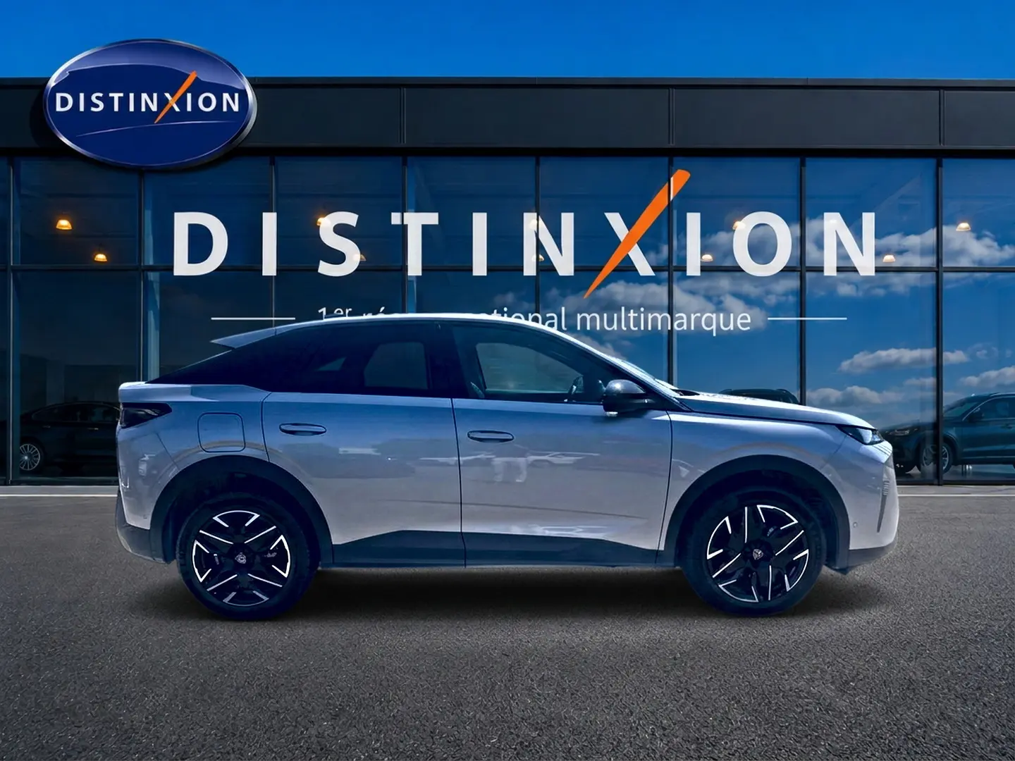 Profil côté gauche du Peugeot 3008 gris 2025 devant une vitrine avec logo Distinxion.