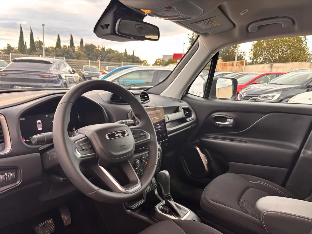 Vue intérieure côté conducteur du Jeep Renegade blanc 2024, avec volant multifonction et écran tactile central visible.
