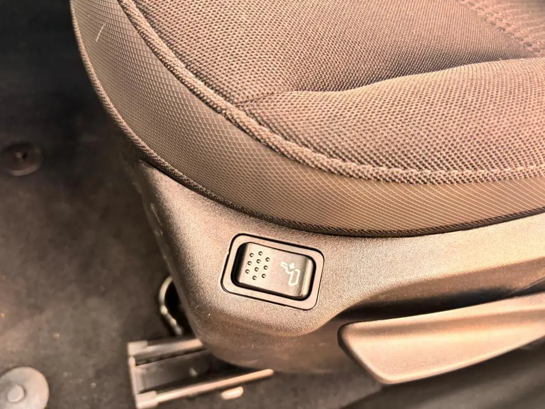 Bouton de réglage de siège chauffant sur le côté gauche d’un siège en tissu beige dans un Jeep Renegade 2024.