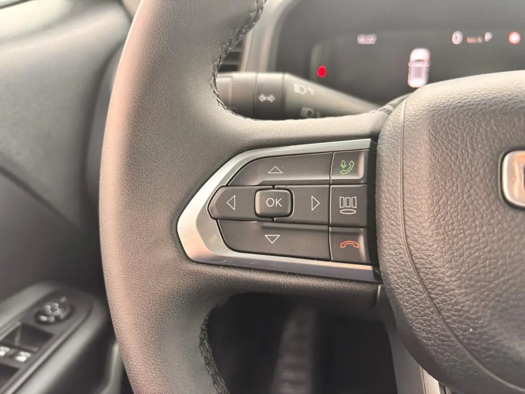 Gros plan sur les commandes au volant côté gauche du Jeep Renegade 2024, avec boutons multifonctions et finition noire.