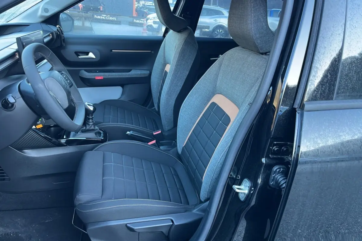 Vue intérieure côté conducteur de la Citroën C3 Aircross noire, sièges tissu bi-matière gris et noir avec surpiqûres.
