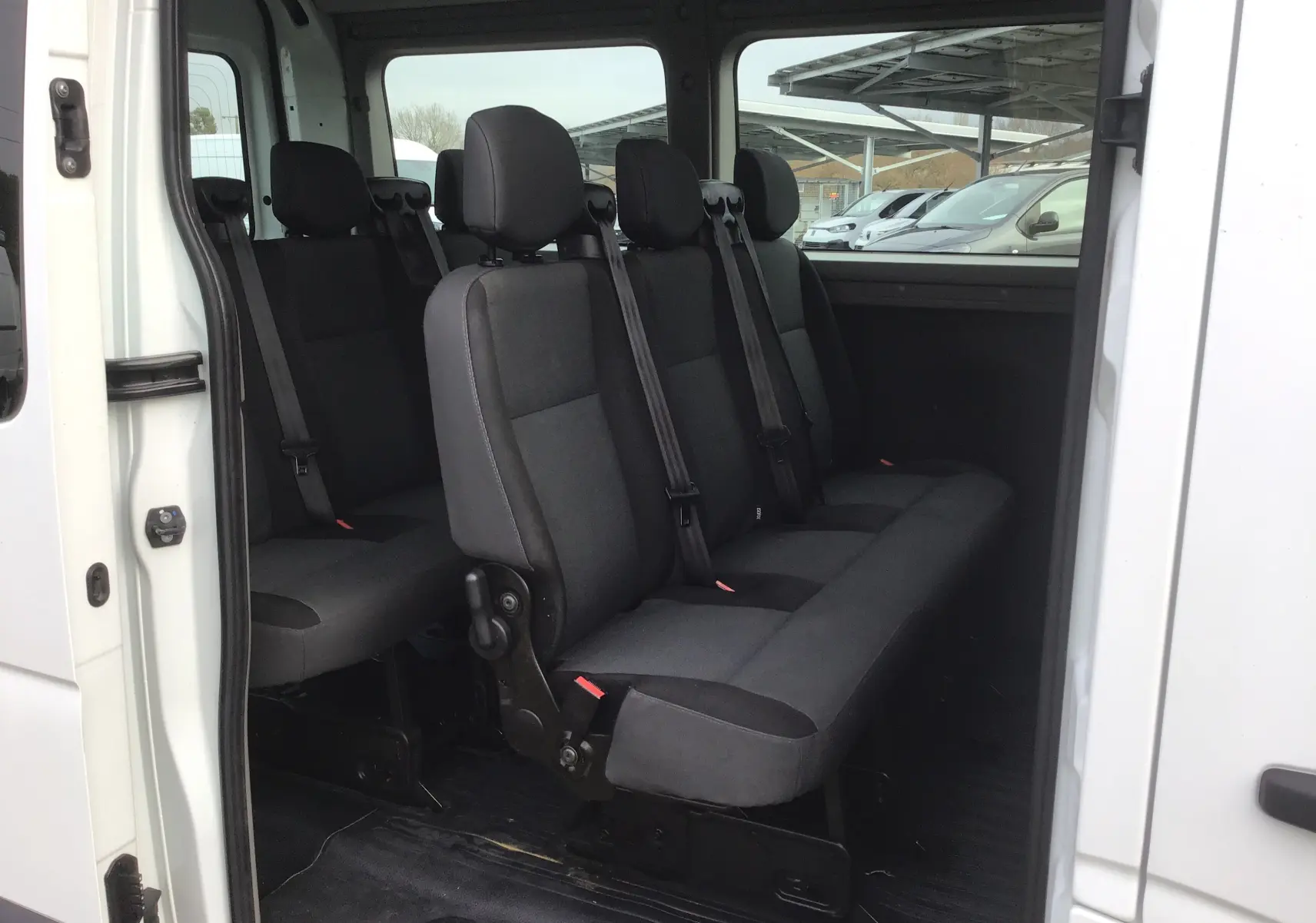 Vue intérieure latérale droite du Renault Master Combi III blanc 2017, montrant les sièges passagers en tissu noir.