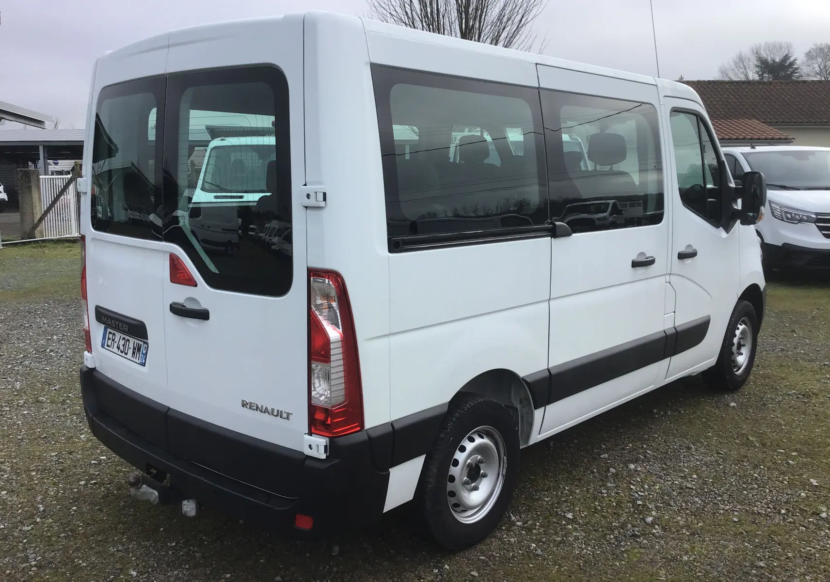 Vue 3/4 arrière droite d’un Renault Master Combi III blanc de 2017 avec vitres latérales teintées et attelage.