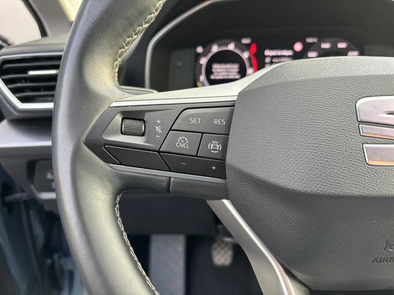 Gros plan sur le volant cuir multifonction du SEAT Leon 2.0 TDI 115 Style avec commandes de régulateur de vitesse.