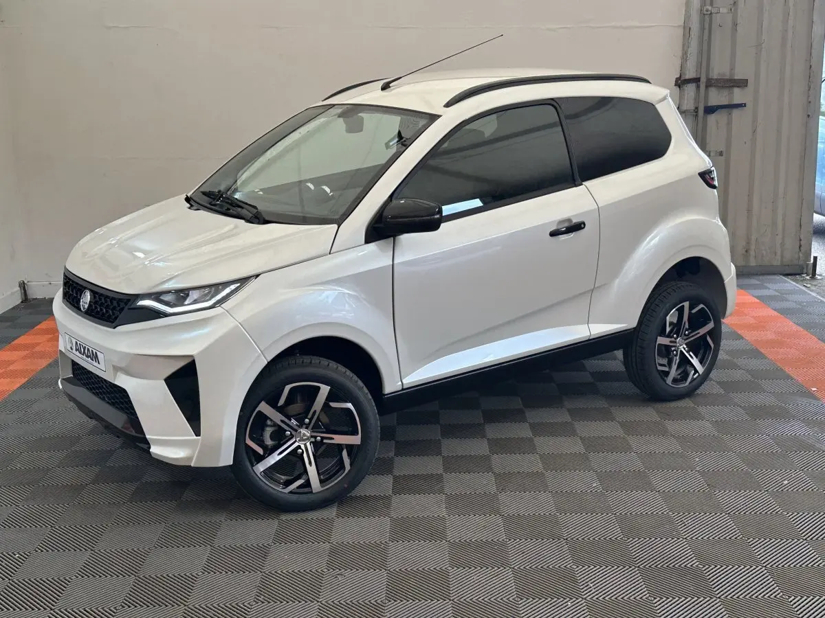 Aixam Ambition 0.5 Crossover Premium blanc, vue 3/4 avant droit, avec rétroviseur caméra côté gauche visible.