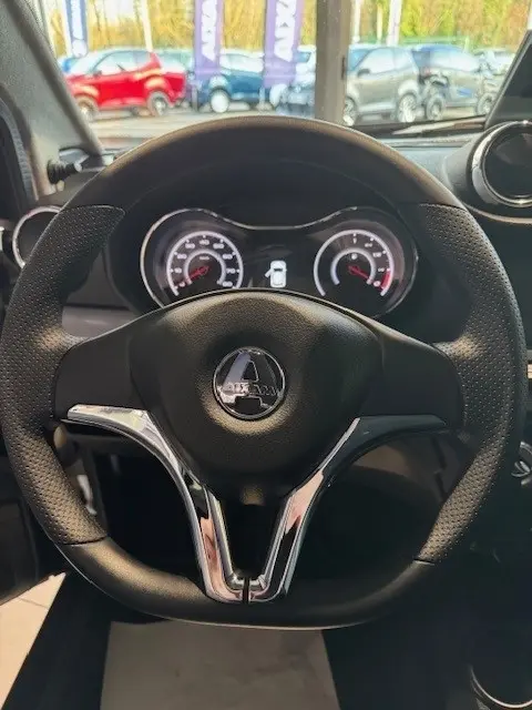 Vue intérieure centrée sur le volant noir de l'AIXAM AMBITION 0.5 CROSSOVER PREMIUM 2026, avec tableau de bord éclairé.