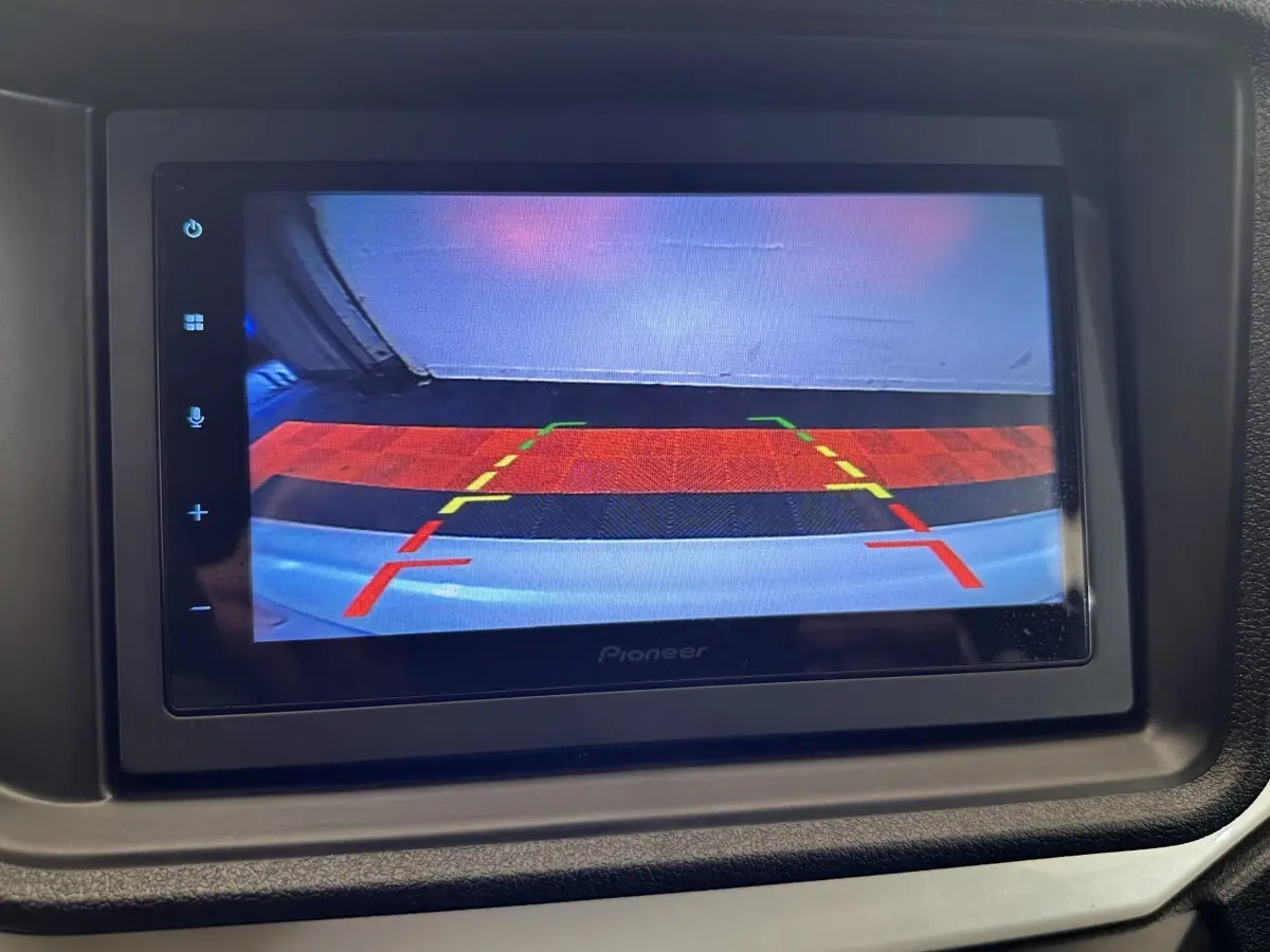 Écran de caméra de recul affichant les lignes de guidage, dans l'habitacle d'une Aixam Ambition blanche 2026.