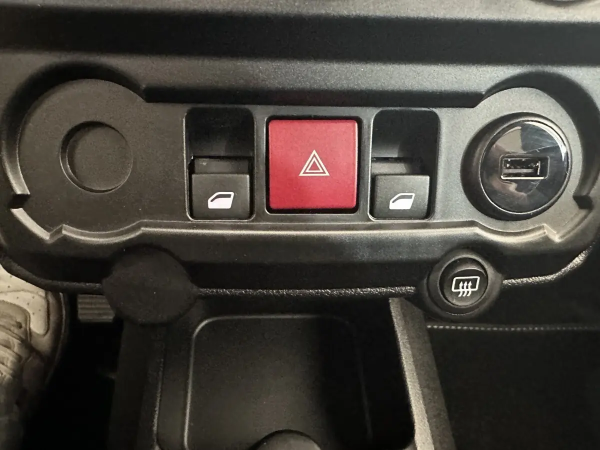 Gros plan sur la console centrale noire de l'AIXAM AMBITION 0.5 CROSSOVER PREMIUM avec boutons de vitres et alerte.