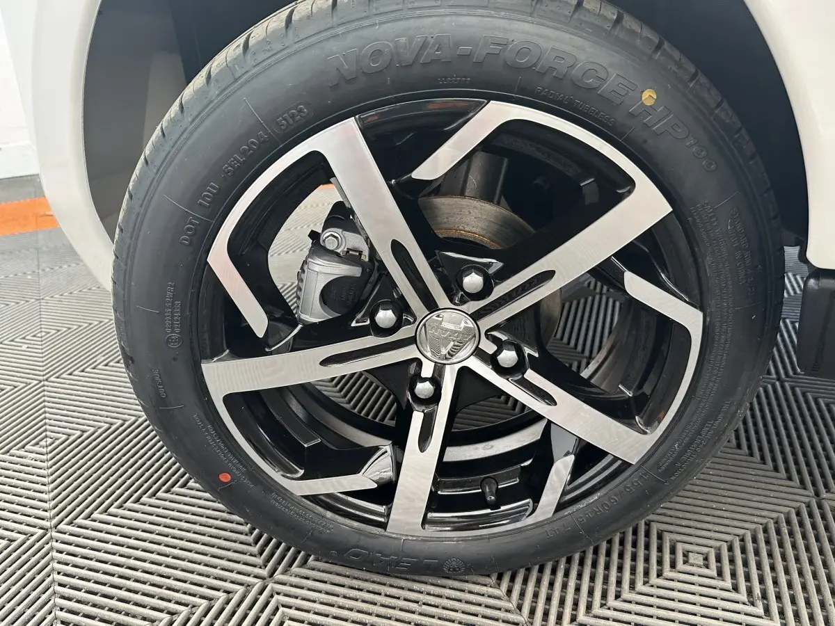 Gros plan sur la roue avant droite de l'AIXAM AMBITION 0.5 CROSSOVER PREMIUM blanche avec jante noire et argentée.