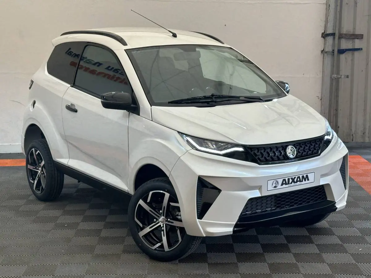 Vue 3/4 avant droit d'une Aixam Ambition 0.5 Crossover Premium blanche avec jantes noires et rétroviseur caméra côté gauche.