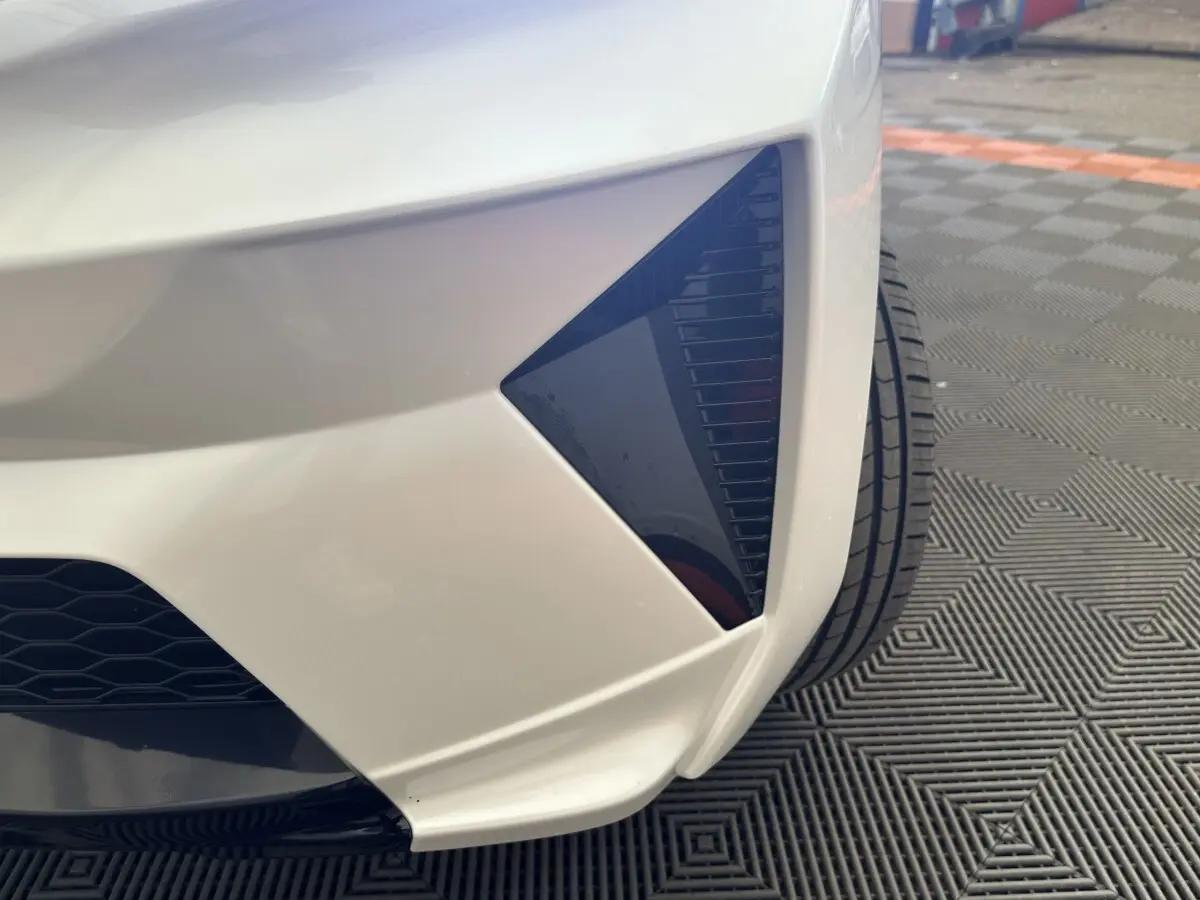 Gros plan sur l’angle avant droit blanc de l’AIXAM AMBITION 0.5 CROSSOVER PREMIUM avec détail noir brillant.