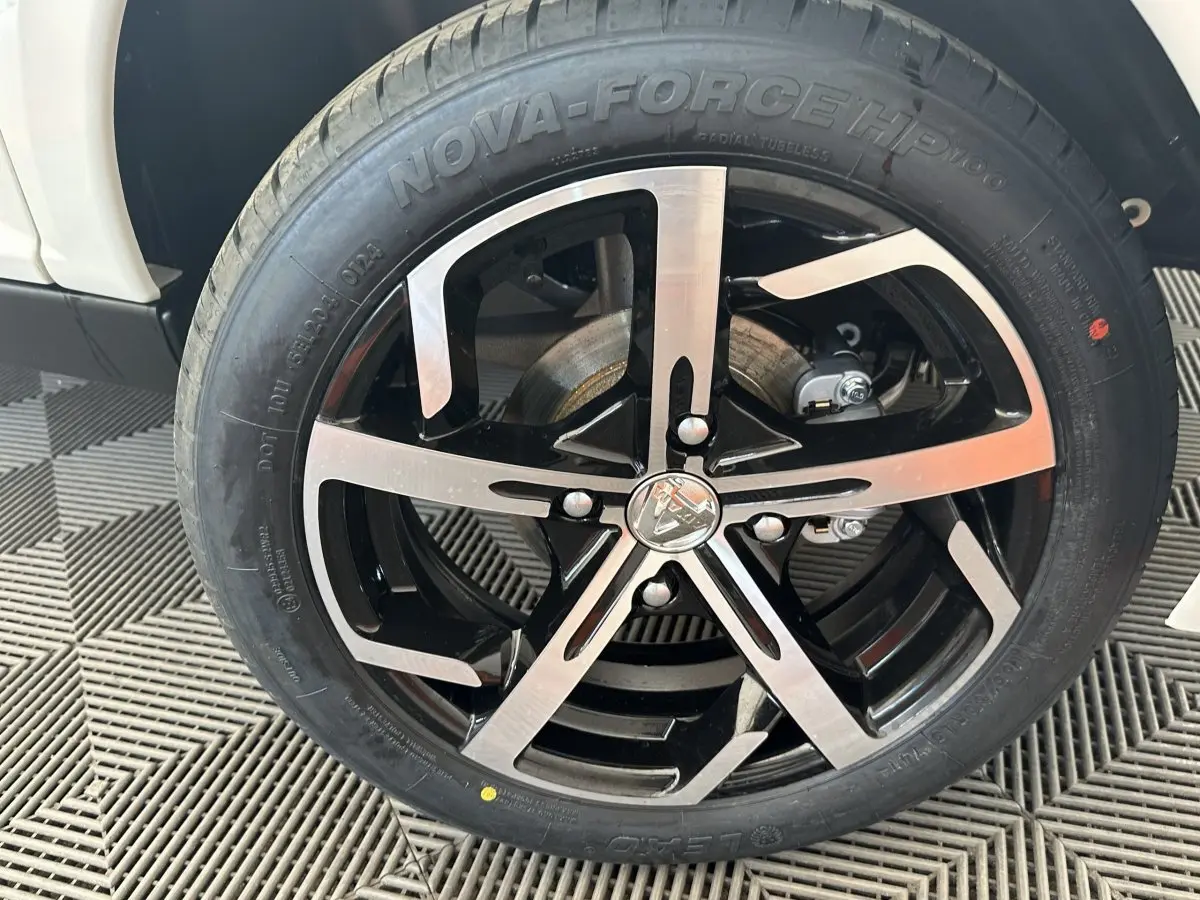 Gros plan sur la roue avant droite d’une Aixam Ambition 0.5 Crossover Premium blanche, jante noire et argentée.