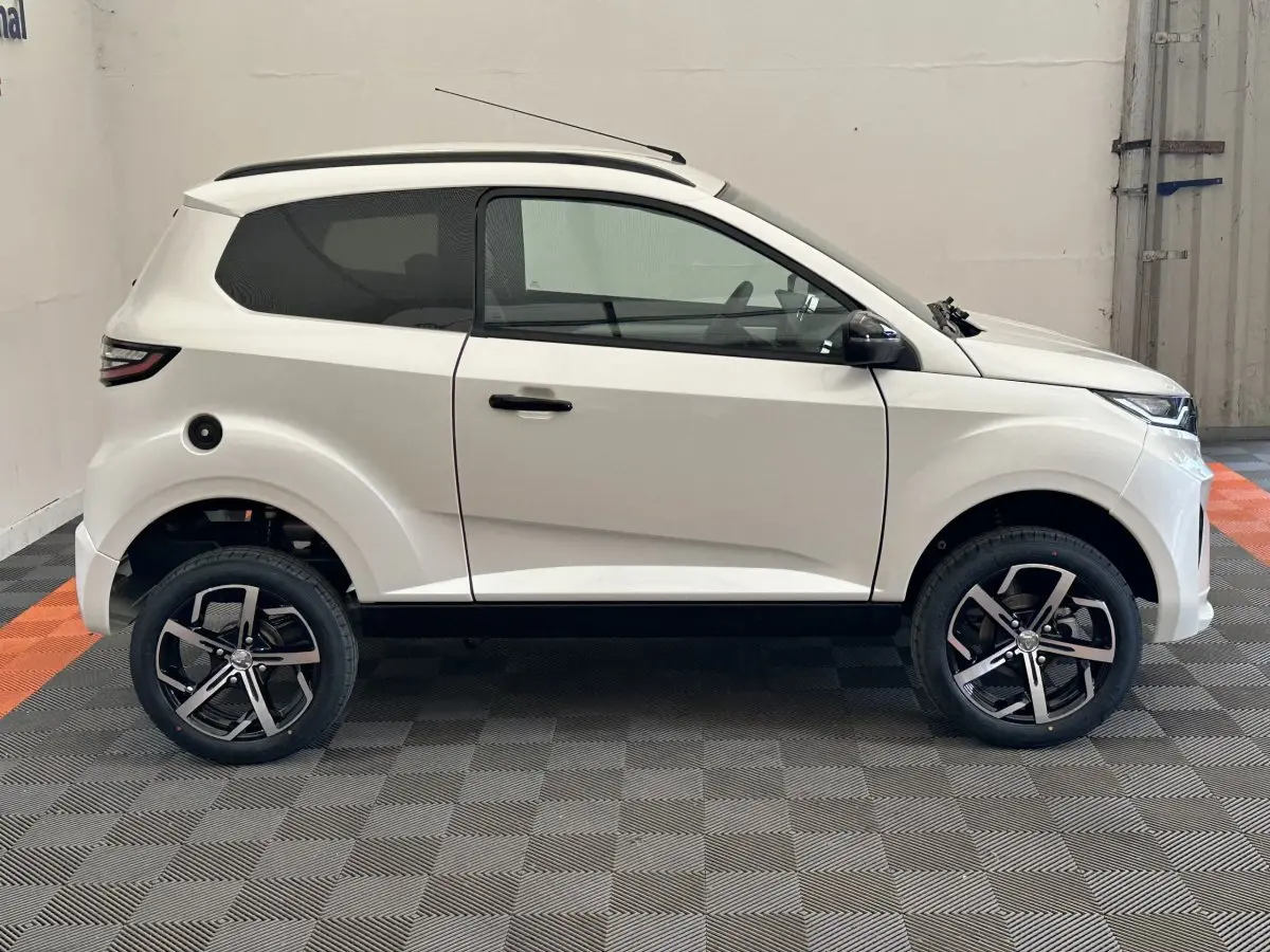 Vue de profil côté gauche d'une Aixam Ambition 0.5 Crossover Premium blanche avec rétroviseur caméra et jantes noires.