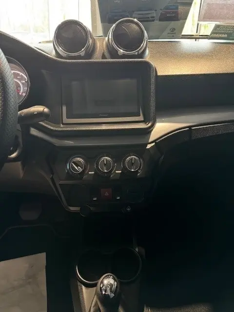 Vue intérieure centrée sur la console centrale de l'AIXAM AMBITION 0.5 CROSSOVER PREMIUM blanche, avec écran tactile et commandes de climatisation.