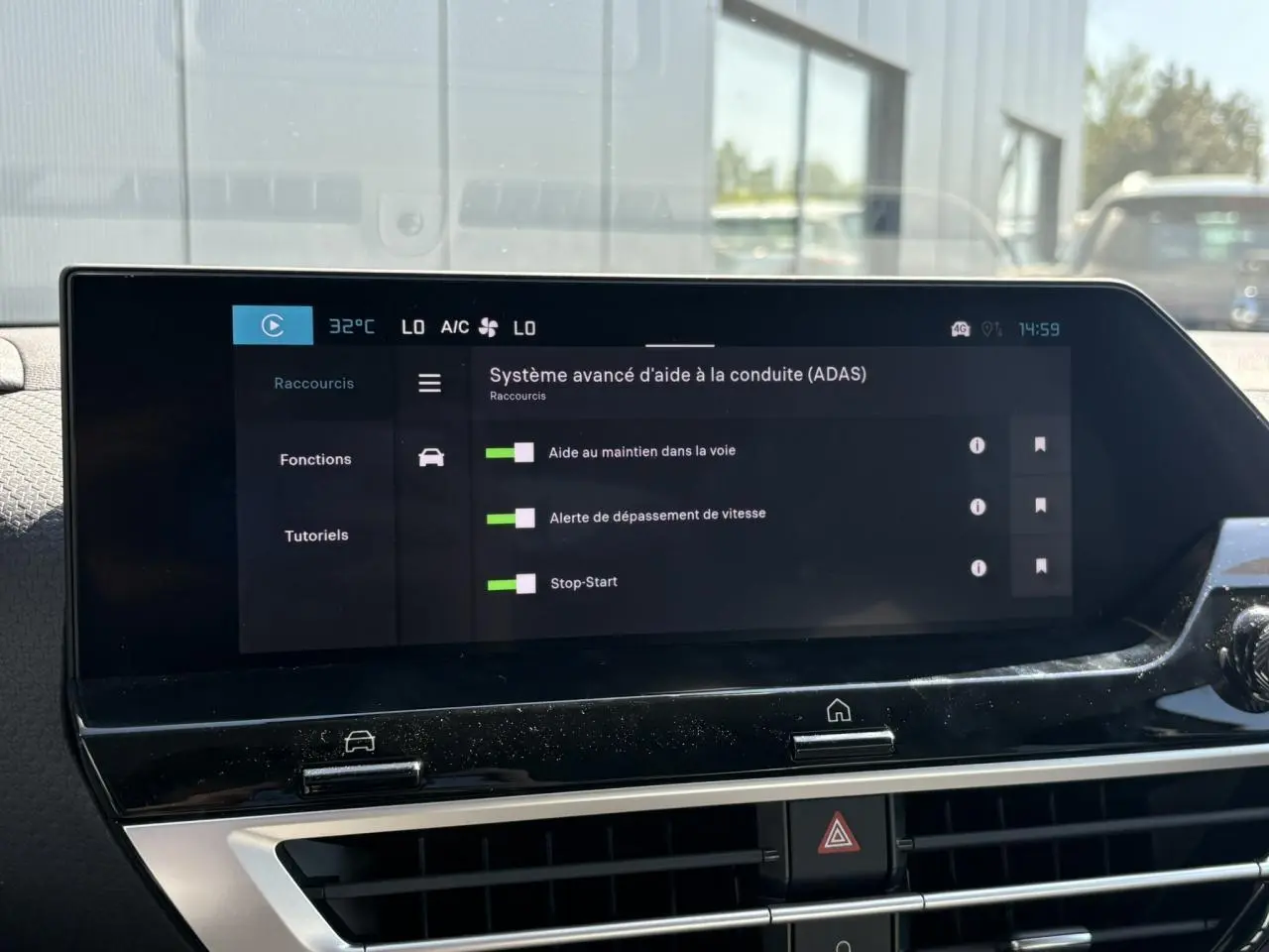 Écran tactile central du tableau de bord de la Citroën C4 Hybrid 145 blanc montrant les aides à la conduite activées.