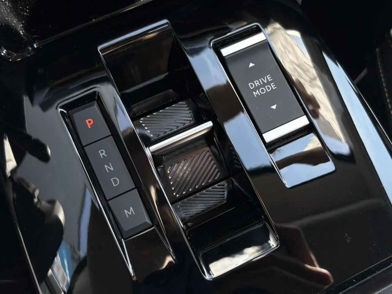 Gros plan sur la console centrale noire brillante avec commandes de boîte auto et bouton Drive Mode du Citroën C4 Hybrid blanc.