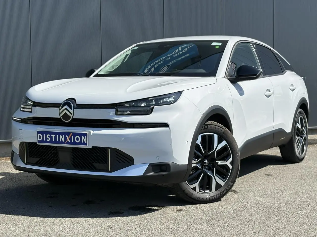 Vue 3/4 avant d'une Citroën C4 Hybrid 145 blanche Okénite avec jantes alliage 18'' diamantées et calandre noire.