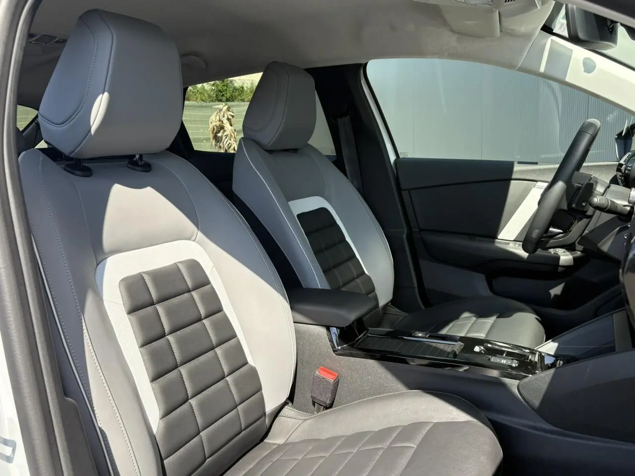 Vue intérieure côté droit des sièges avant gris clair et noir de la Citroën C4 Hybrid 2025 avec console centrale brillante.