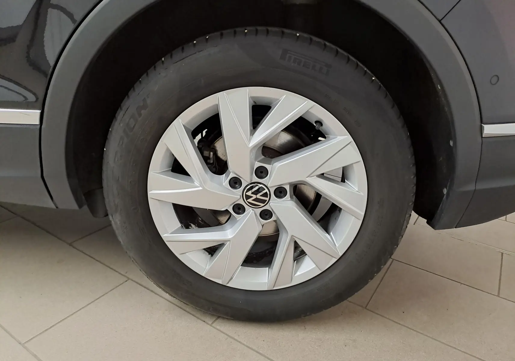 Gros plan sur la roue avant gauche du Volkswagen Tiguan noir intense, mettant en valeur la jante alliage et le pneu Pirelli.