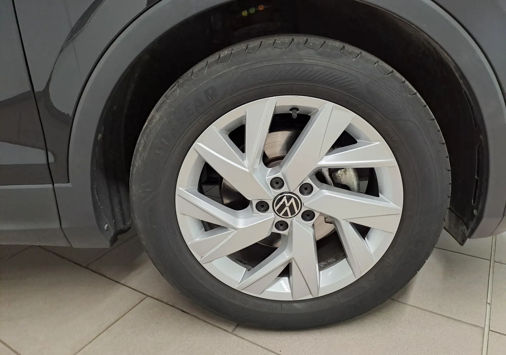 Gros plan sur la roue avant gauche du Volkswagen Tiguan noir intense, mettant en valeur la jante argentée au design moderne.